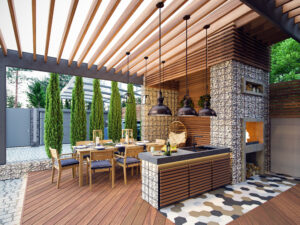 Luxury outdoor living space blending modern Palm Springs design with natural textures and Southern warmth—featuring a wood pergola, stone kitchen, and stylish dining area by Spaces by JohnRoss.