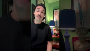 JohnRoss sharing interior design tips for mental health in a green room with eclectic decor, including a blue lamp and classical sculpture.