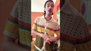 JohnRoss wearing a vintage crochet shirt in a warm-toned room, explaining story-driven interior design tips for creating timeless and meaningful homes.