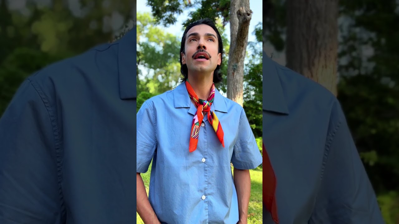 JohnRoss wearing a blue shirt and colorful scarf outdoors, explaining timeless interior design principles and how refinement goes beyond expensive trends.